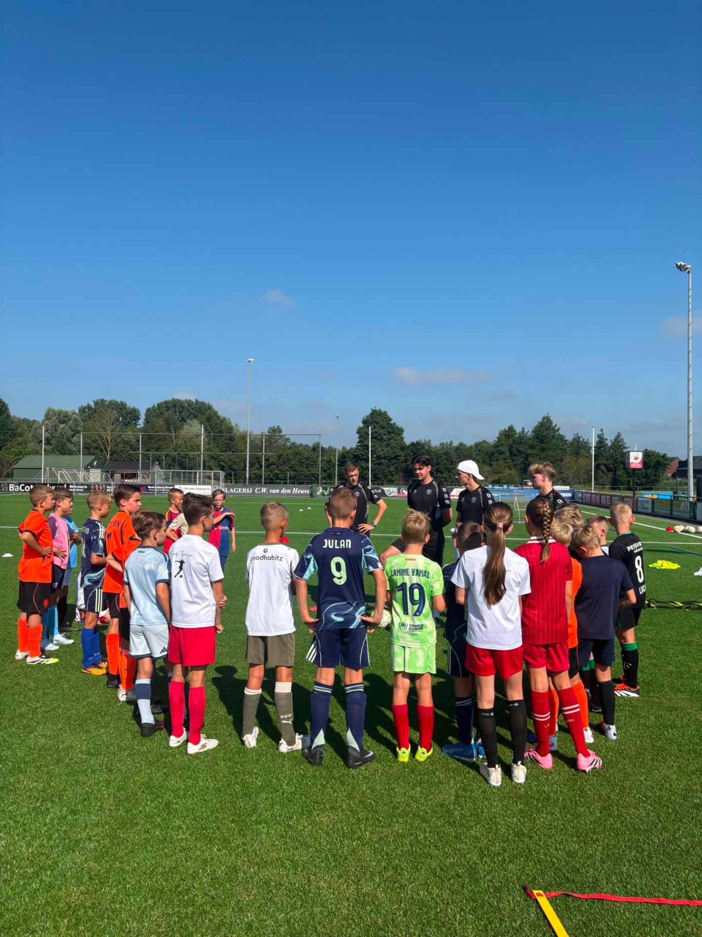 Groep spelers luistert in een cirkel naar de trainers