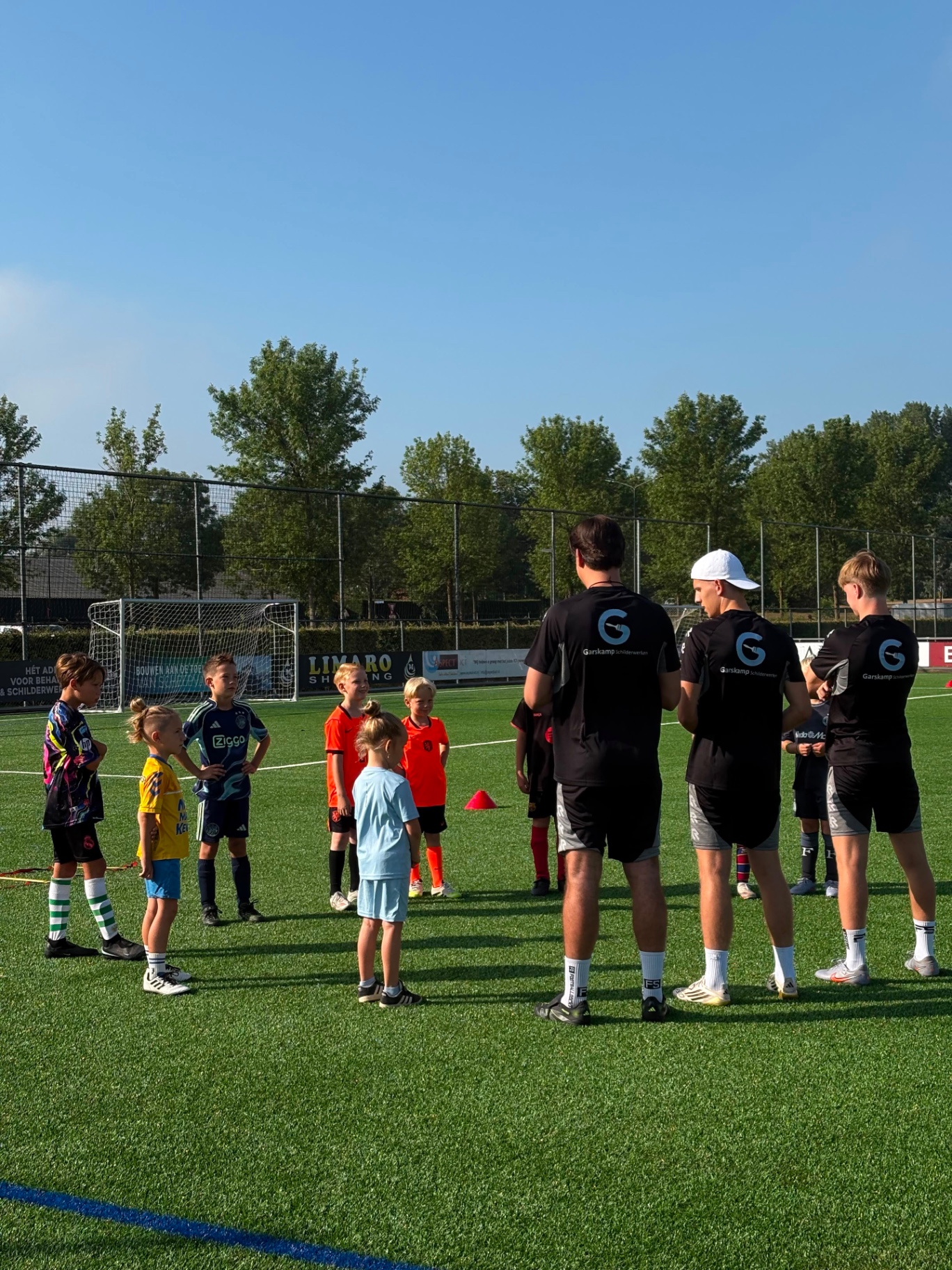 Trainers van Voetbalschool Vision briefen een groep jeugdspelers